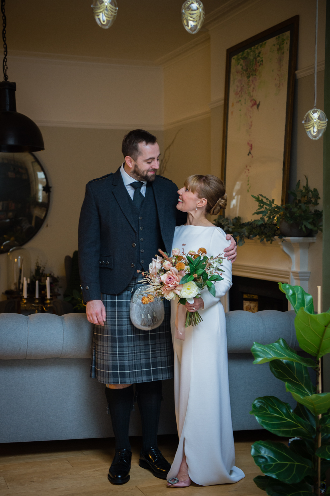 A groom wearing a kilt and a bride wearing a Roland Mouret bridal gown on their wedding day